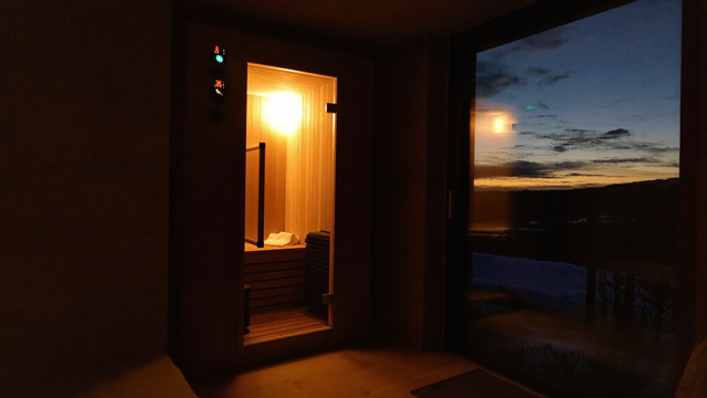 Home infrared sauna glowing warmly in a dark room at night