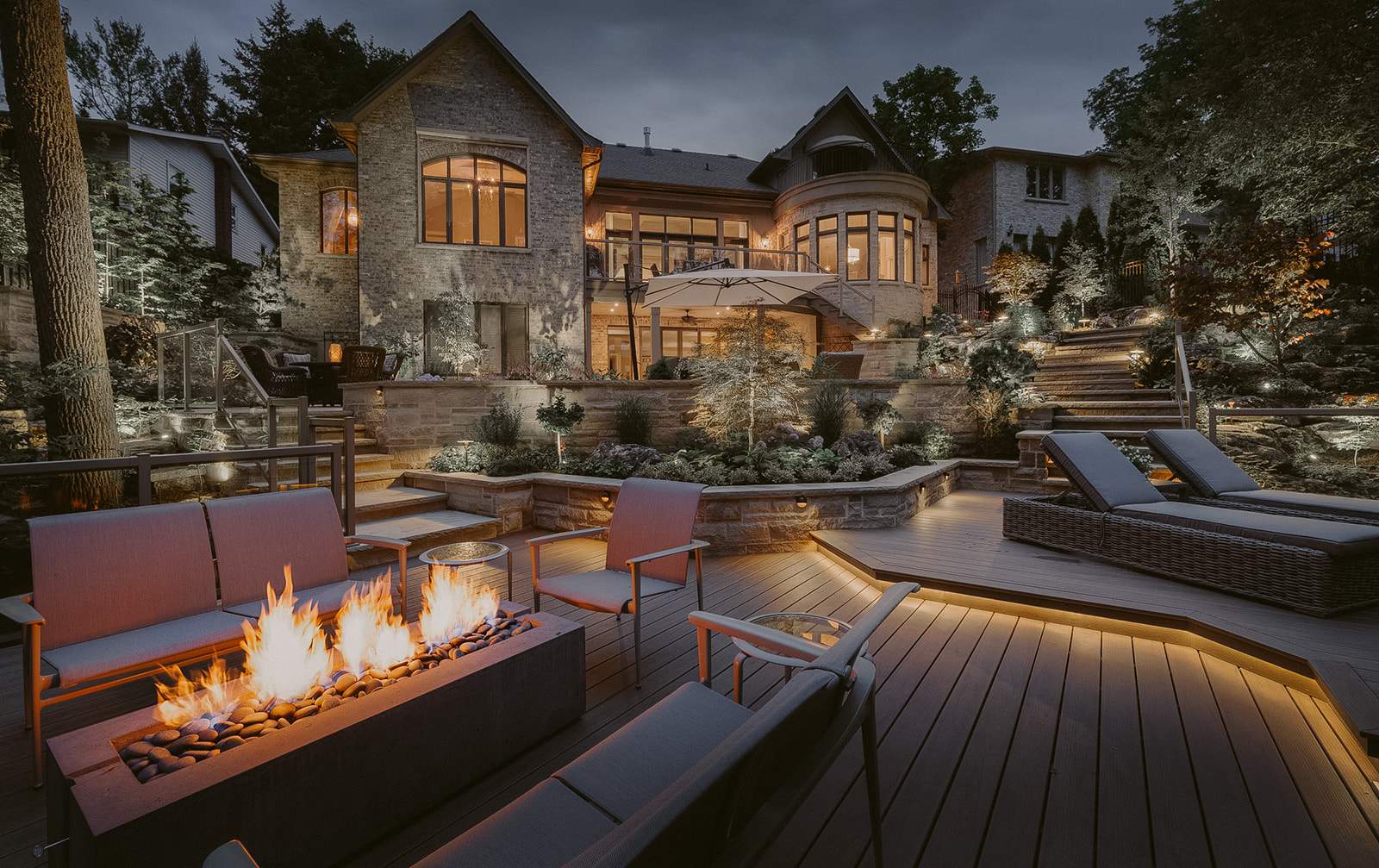 HPC Dekko Avera 60 concrete fire table in Charcoal with Slate Beachstone media, lit on an open deck at dusk