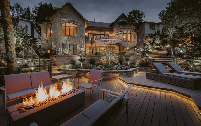 HPC Dekko Avera 60 concrete fire table in Charcoal with Slate Beachstone media, lit on an open deck at dusk