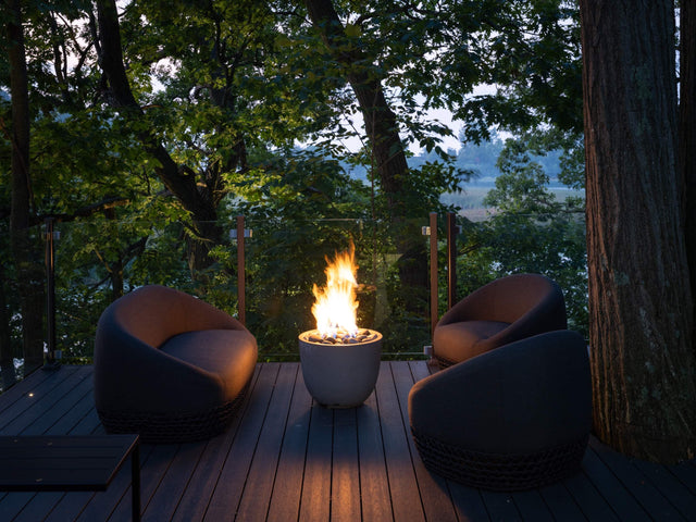 HPC Dekko Element concrete fire table in Ash with Ivory Beachstone media, lit at dusk on a timber deck