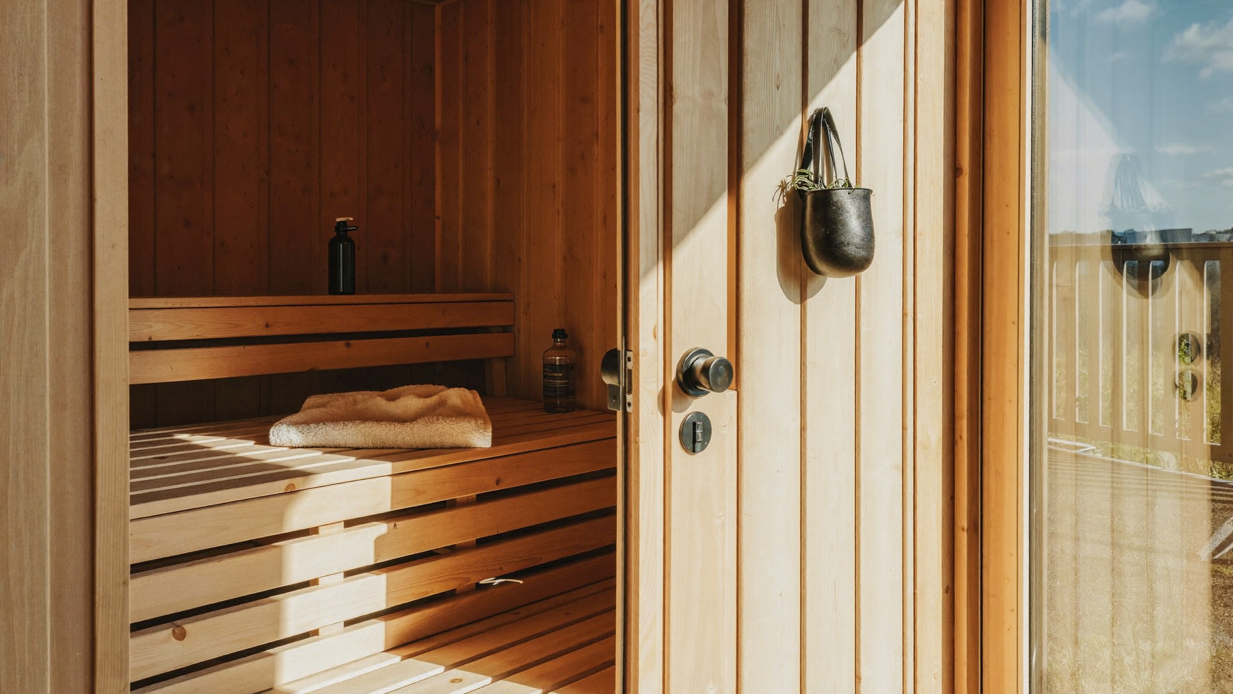 Warm hemlock infrared sauna interior with towel and water bottle in morning light