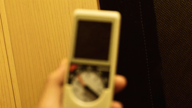 Handheld EMF meter held near an infrared sauna heater panel